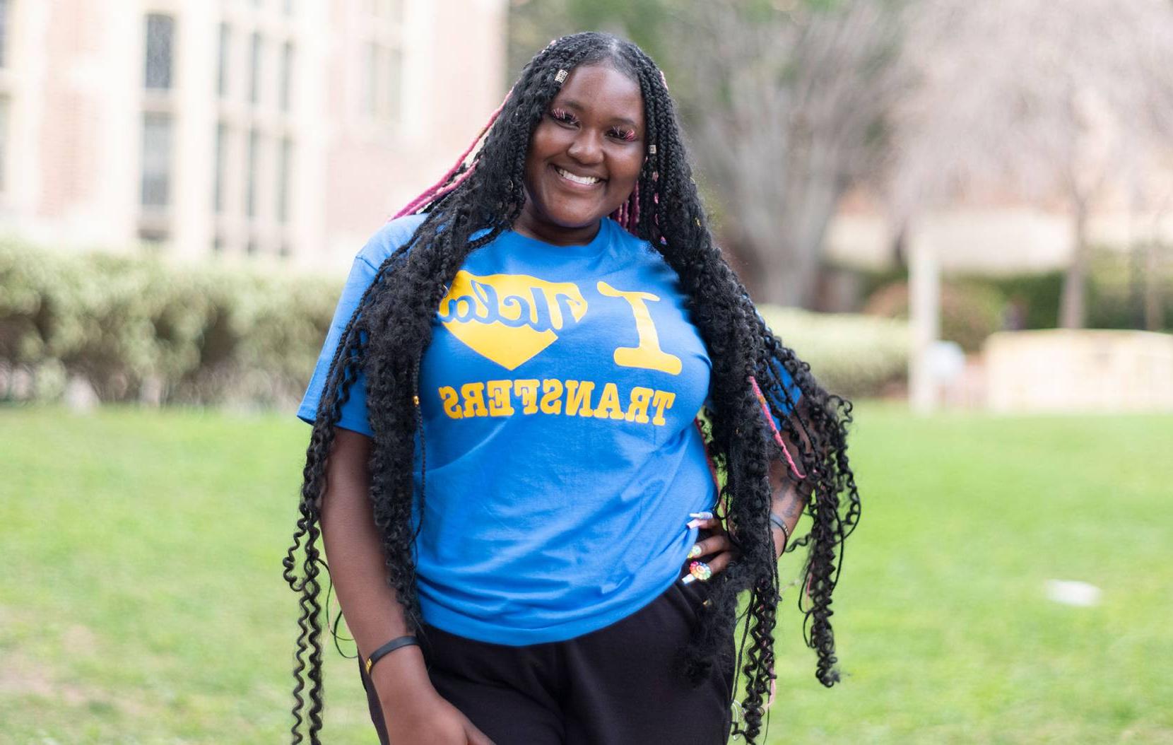 Student posing in a blue tshirt that says "I love UCLA transfers"